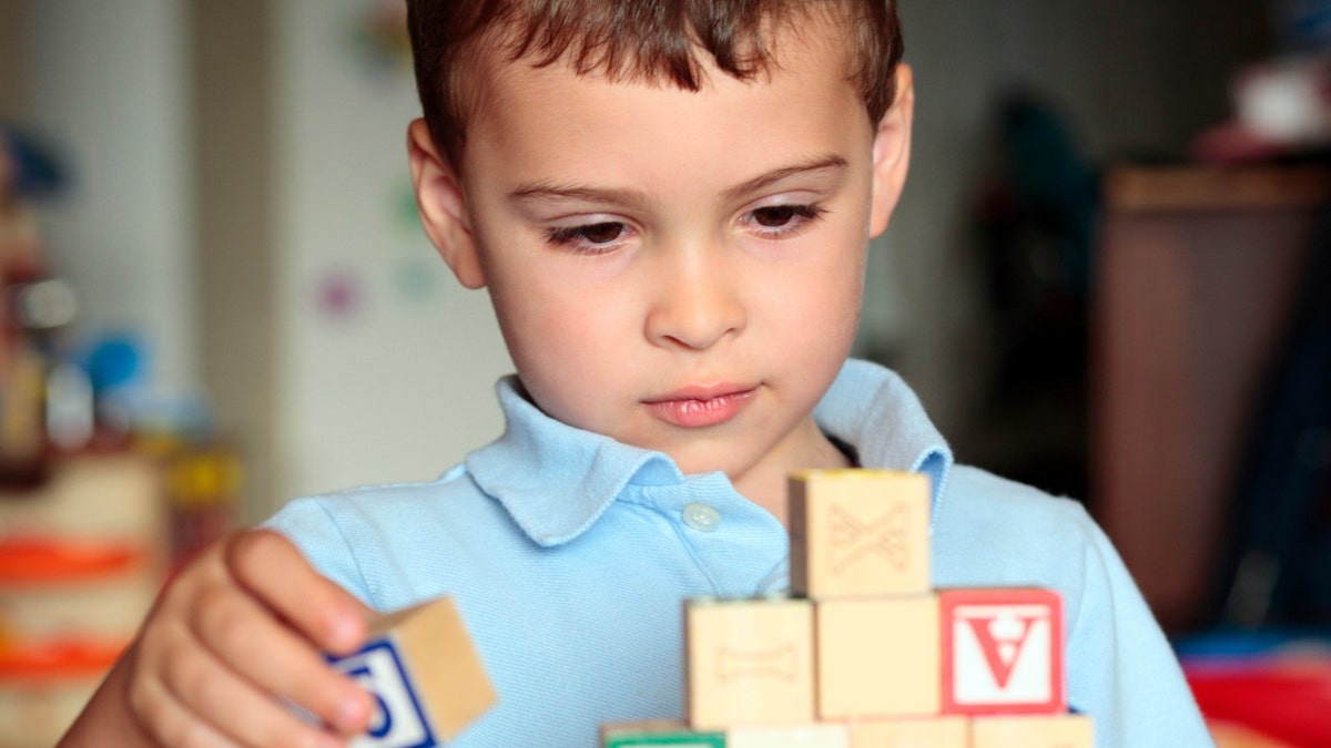 Child deciding where is the best place to put his block. 