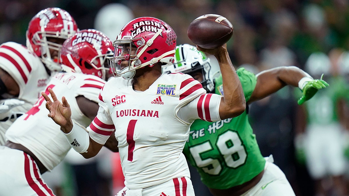 Louisiana-Lafayette quarterback Levi Lewis (1) passes under pressure from Marshall defensive lineman Elijah Alston (58) in the first half of the New Orleans Bowl NCAA football game in New Orleans, Saturday, Dec. 18, 2021.