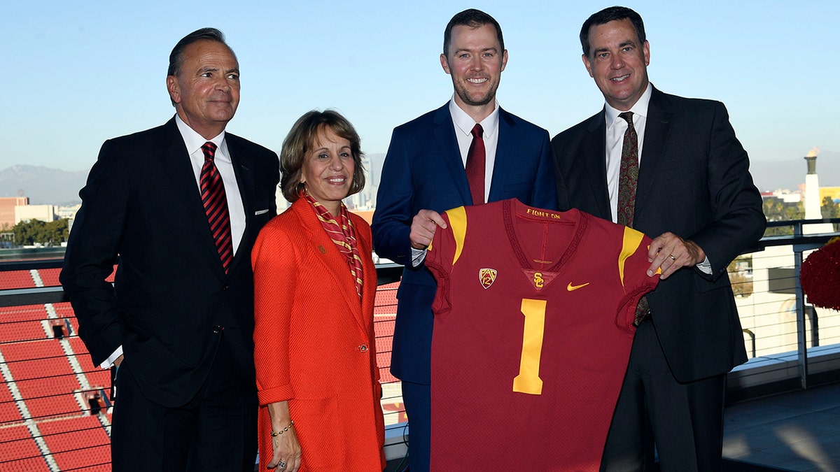 New USC football coach Lincoln Riley (center) posses with USC Board of Trustees Chair Rick Caruso (left) university president Carol L. Folt and athletic director Mike Bohn (right) during a news conference in the 1923 Club at the Los Angeles Coliseum Nov. 29, 2021.