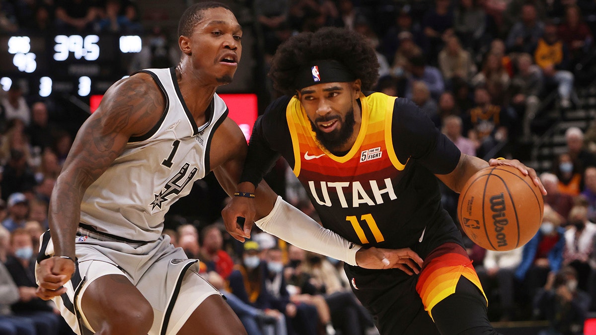 Utah Jazz guard Mike Conley (11) drives the basket as San Antonio Spurs guard Lonnie Walker IV (1) defends during the second half of an NBA basketball game on Friday, Dec. 17 2021, in Salt Lake City.