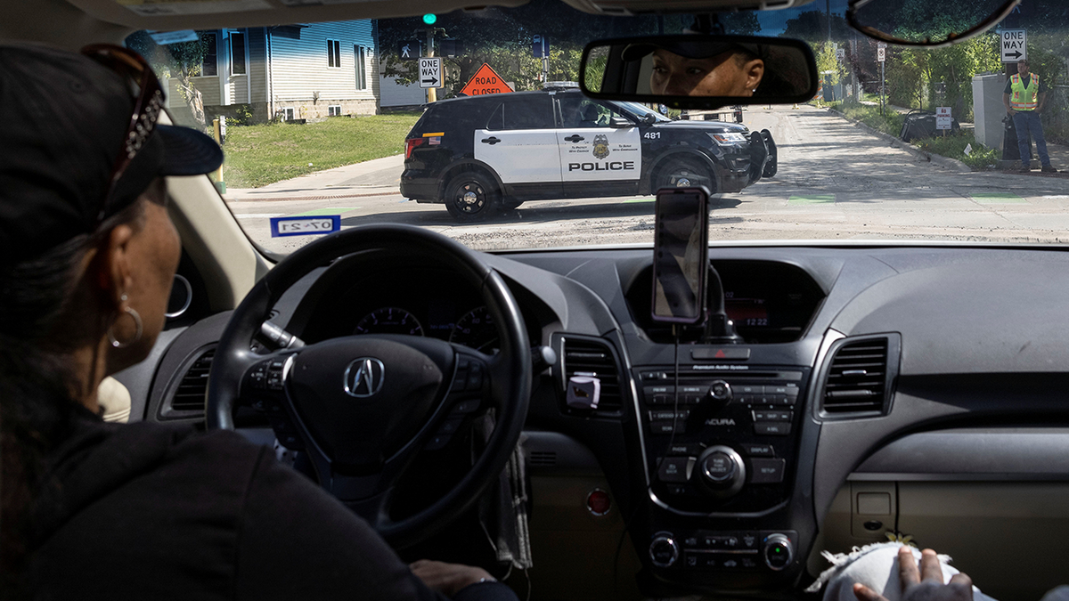 A local resident looks at a police vehicle driving along a street in north of Minneapolis, Minnesota, U.S. September 9, 2021.