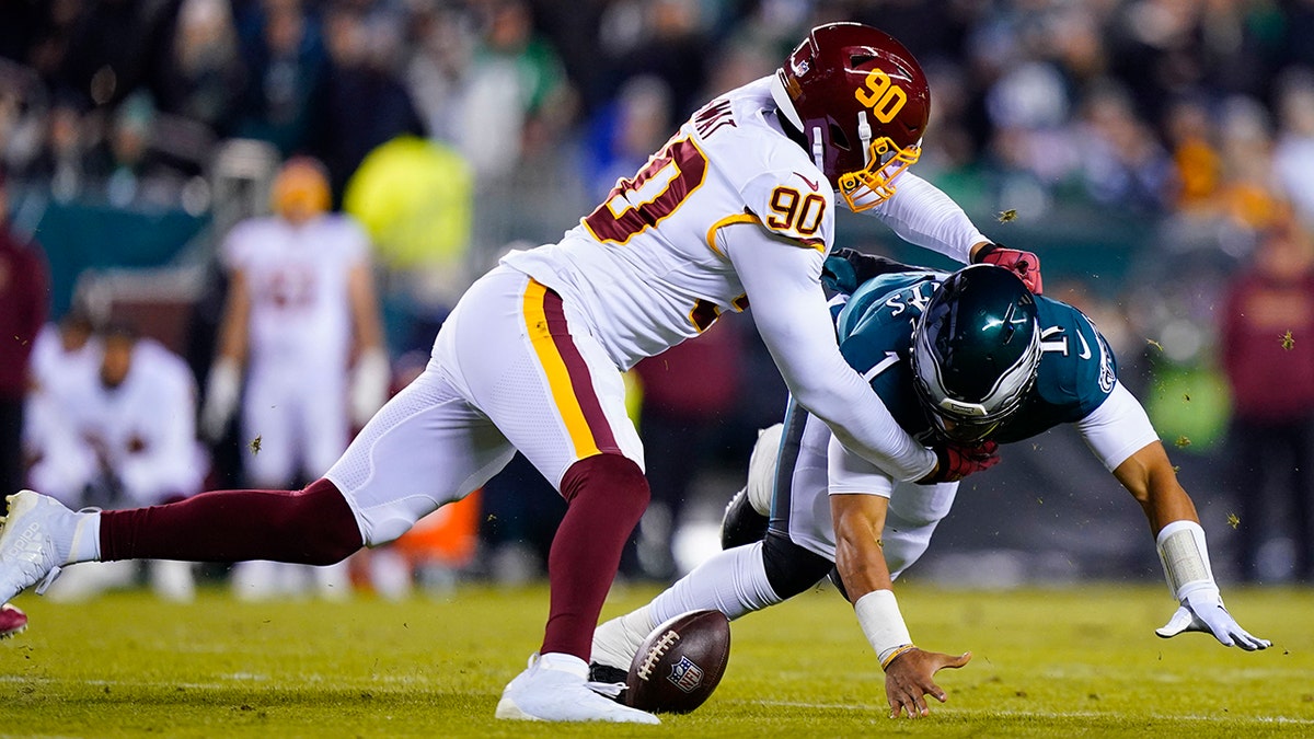 Philadelphia Eagles quarterback Jalen Hurts, right, fumbles the ball as he is hit by Washington Football Team's Montez Sweat during the first half of an NFL football game, Tuesday, Dec. 21, 2021, in Philadelphia.