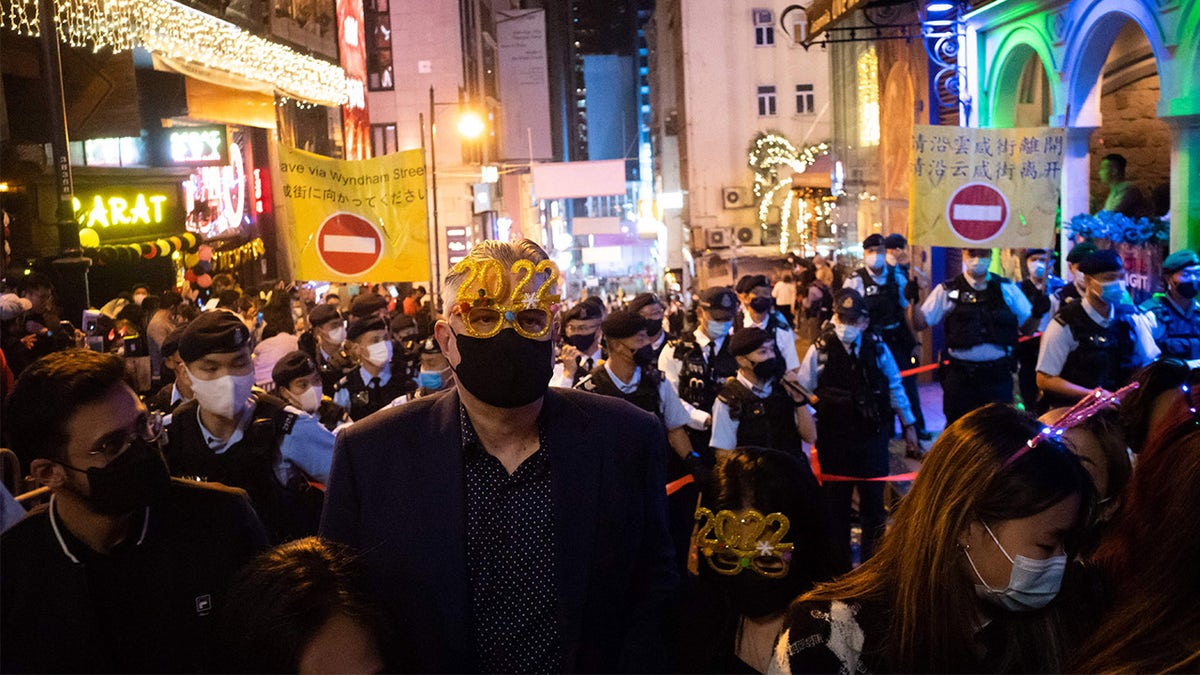 A man wearing festive glasses stands in front of police at Hong Kong's Lan Kwai Fong area on Jan. 1, 2022.