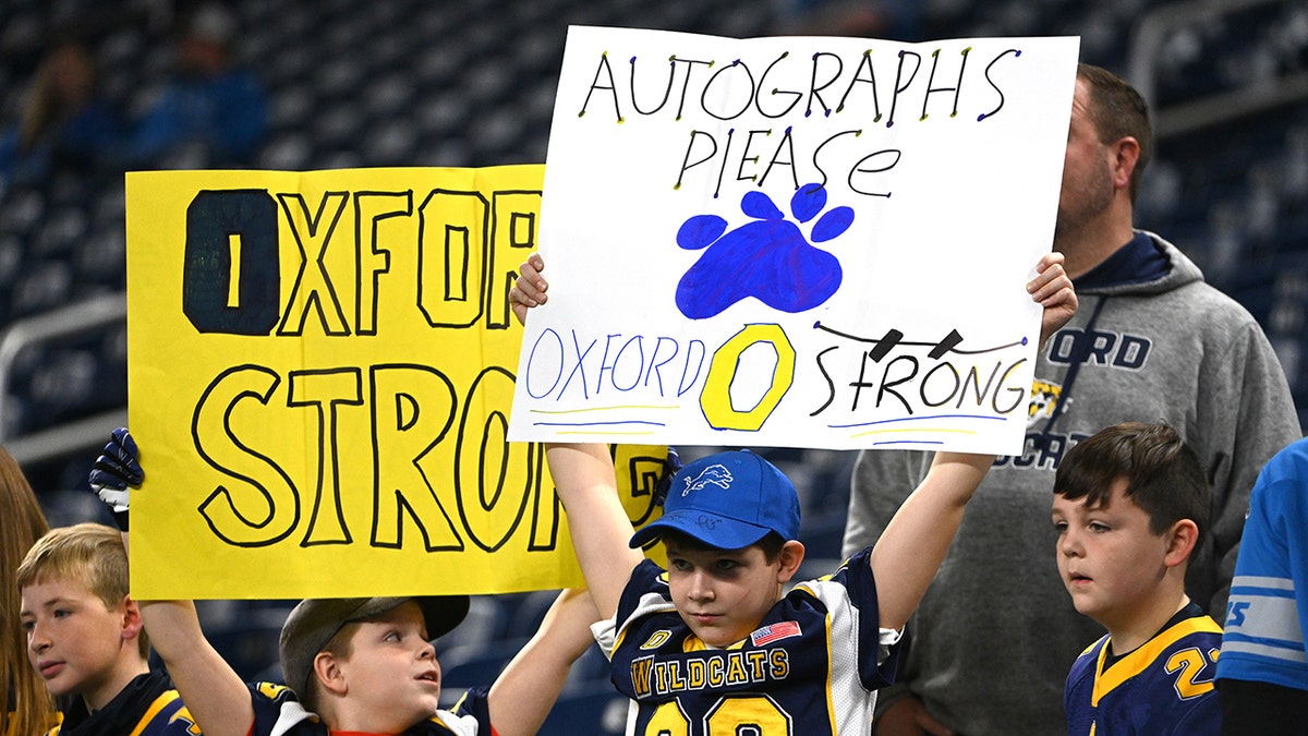 DETROIT, MICHIGAN - DECEMBER 05: Fans in the stands before the game between the Minnesota Vikings and Detroit Lions wearing jerseys and holding signs in support of those killed at Oxford High School football at Ford Field on December 05, 2021 in Detroit, Michigan.