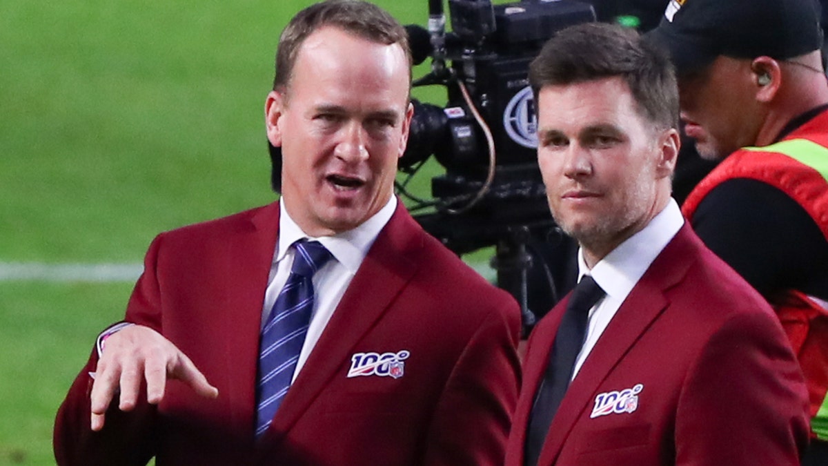 Tom Brady and Peyton Manning talk on the field during the 100-year team celebration prior to Super Bowl LIV on Feb. 2, 2020, at Hard Rock Stadium in Miami Gardens, Florida.