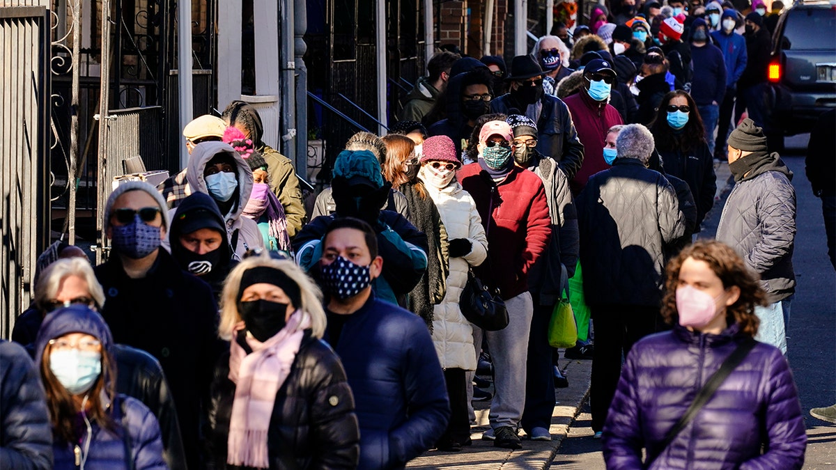 City residents wait in a line extending around the block to receive free at-home rapid COVID-19 test kits