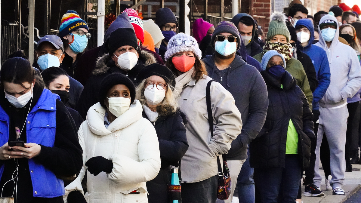 People wait in a line extending around the block to receive free at-home rapid COVID-19 test kits in Philadelphia on Monday, December 21, 2021.
