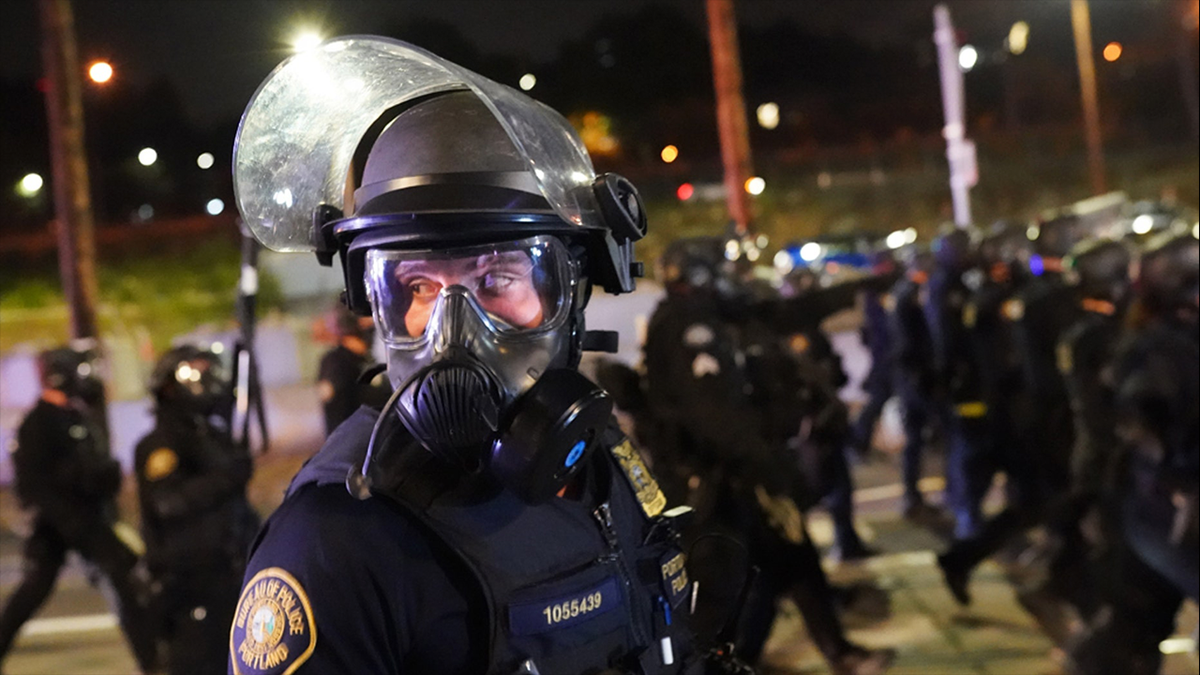 A Portland, Ore., police officer scans the crowd while dispersing protesters, Aug. 21, 2020.?