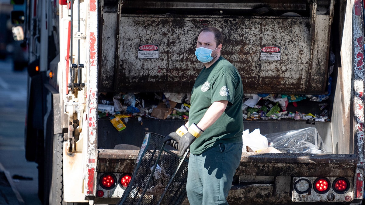FILE: A sanitation worker wearing a mask and gloves collects trash amid the coronavirus pandemic on April 28, 2020 in New York City. (Photo by Alexi Rosenfeld/Getty Images)