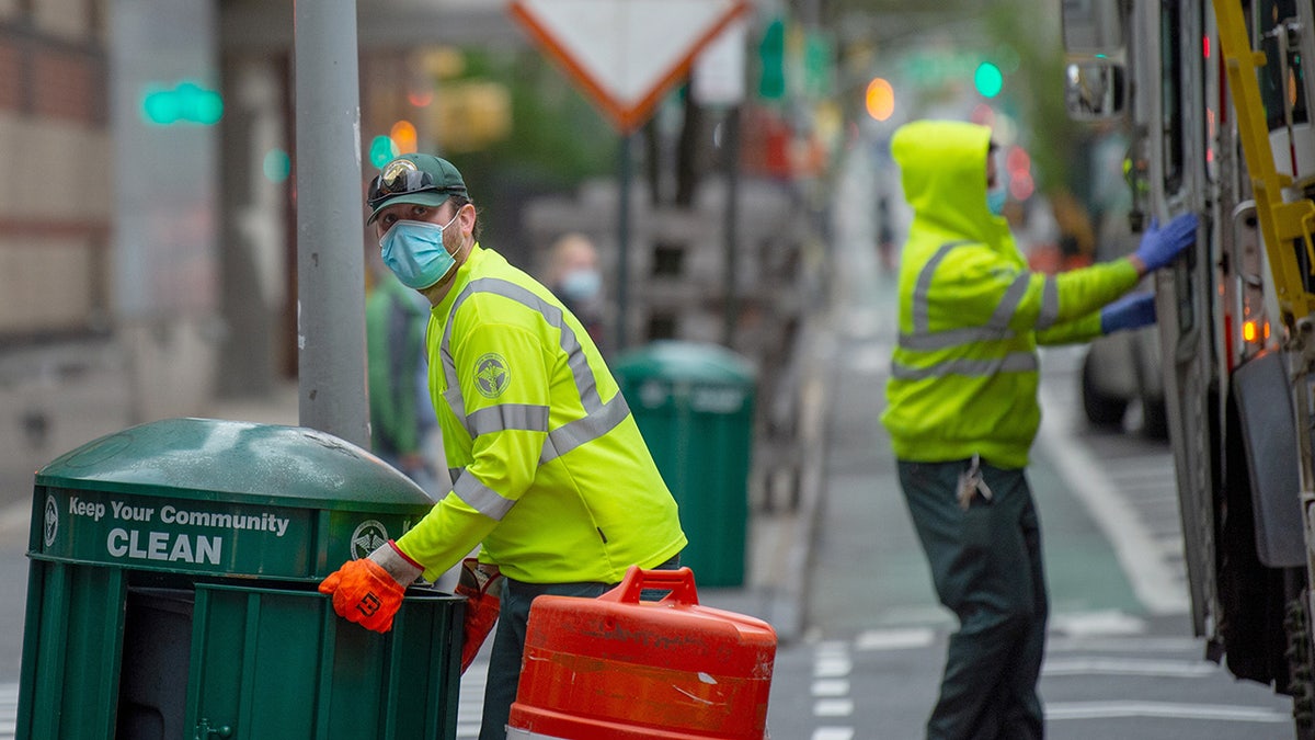 FILE: A New York City Department of Sanitation worker wearing a mask and gloves collects the trash amid the COVID-19 pandemic on April 30, 2020 in New York City. (Photo by Alexi Rosenfeld/Getty Images)
