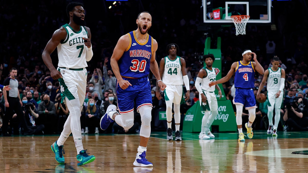 Golden State Warriors guard Stephen Curry (30) reacts after hitting a three point shot as Boston Celtics guard Jaylen Brown (7) looks on during the first half of an NBA basketball game, Friday, Dec. 17, 2021, in Boston.