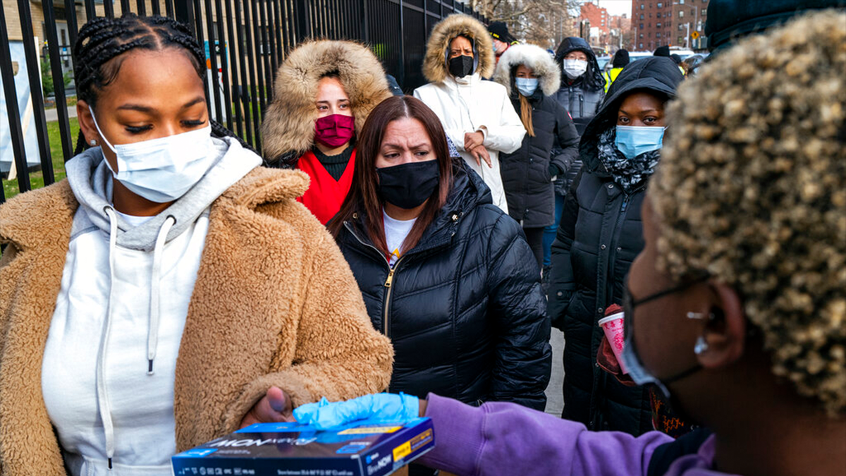 FILE - People line up and receive test kits to detect COVID-19 as they are distributed in New York on Dec. 23, 2021.