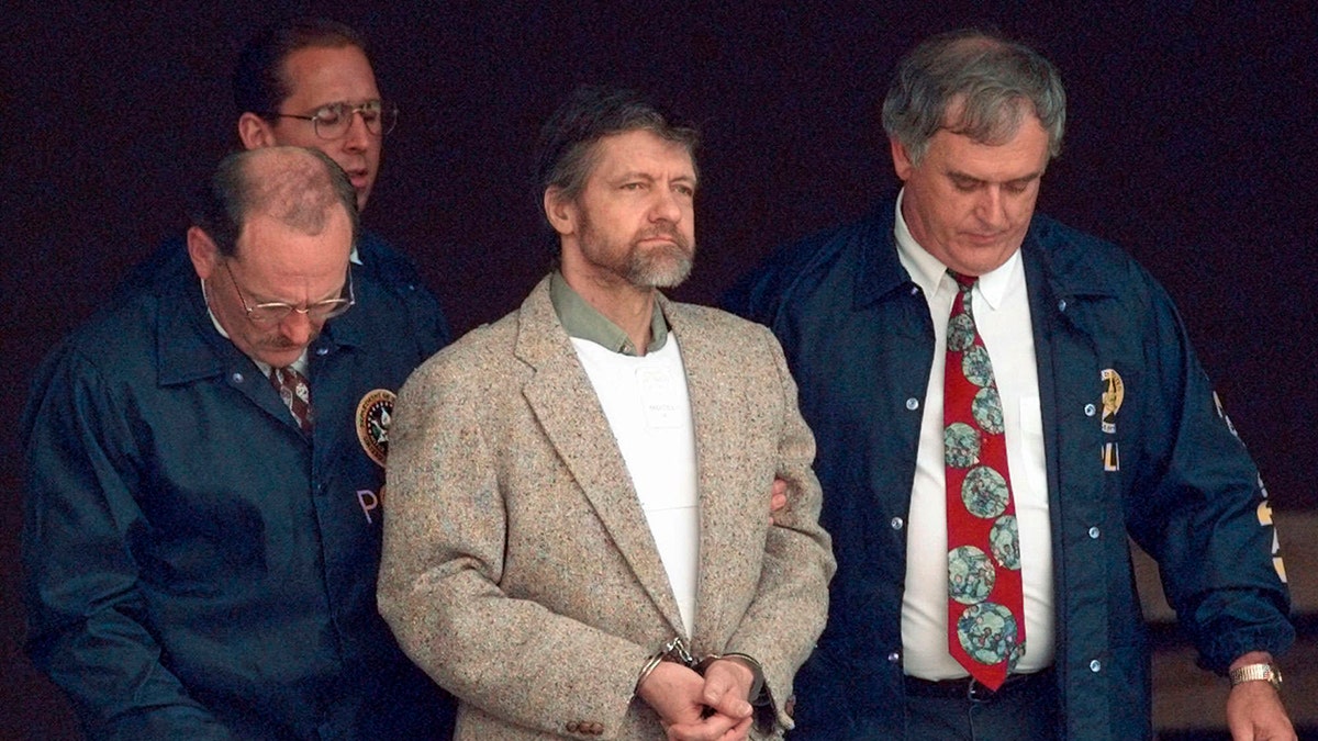 Theodore Kaczynski looks around as U.S. Marshals prepare to take him down the steps at the federal courthouse to a waiting vehicle on June 21, 1996, in Helena, Montana.