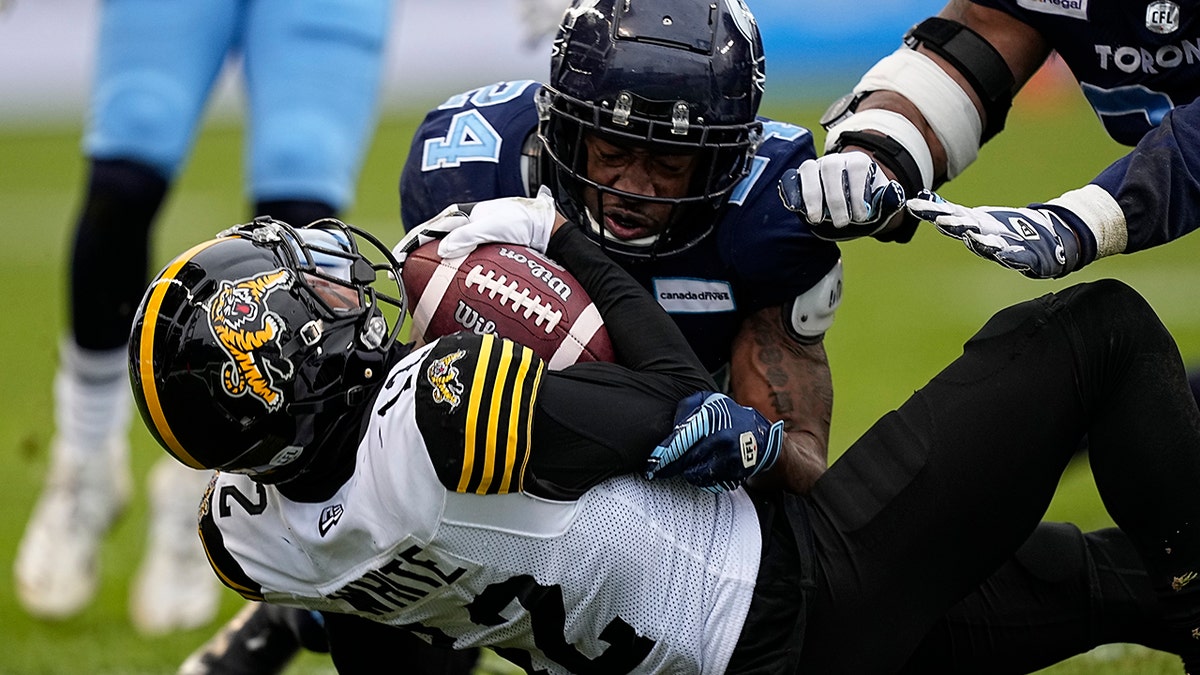 Dec 5, 2021; Toronto, Ontario, CAN; Toronto Argonauts defensive back Crezdon Butler (24) tackles Hamilton Tiger-Cats wide receiver Tim White (12) during the Canadian Football League Eastern Conference Final game at BMO Field. Hamilton defeated Toronto.