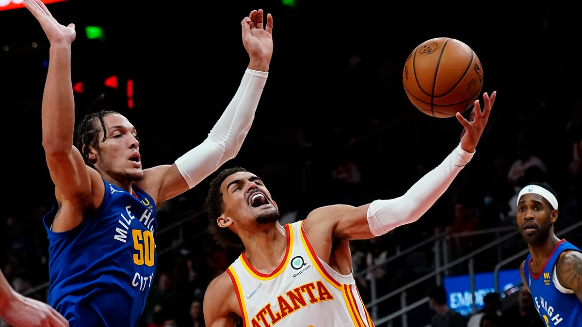 Atlanta Hawks guard Trae Young (11) goes past Denver Nuggets forward Aaron Gordon (50) during the first half of an NBA basketball game Friday, Dec. 17, 2021, in Atlanta.