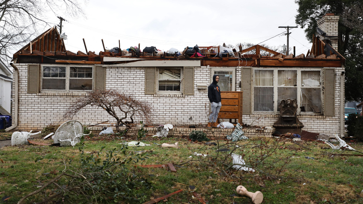 TOPSHOT - A Bowling Green, Kentucky, resident surveys the damage following a tornado that struck the area on December 11, 2021. - Tornadoes ripped through five US states overnight, leaving more than 70 people dead Saturday in Kentucky and causing multiple fatalities at an Amazon warehouse in Illinois that suffered "catastrophic damage" with around 100 people trapped inside. The western Kentucky town of Mayfield was "ground zero" of the storm -- a scene of "massive devastation," one official said. (Photo by Gunnar Word / AFP) (Photo by GUNNAR WORD/AFP via Getty Images)