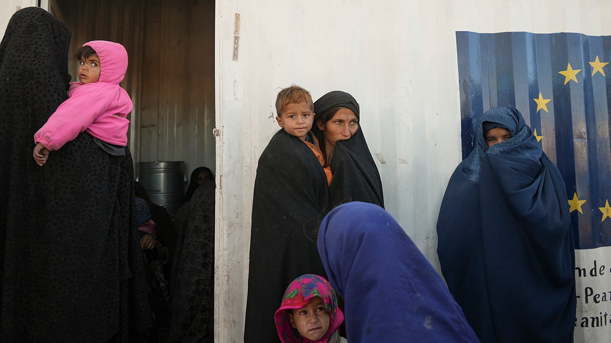 Afghan women gather outside a makeshift clinic organized by World Vision at a settlement near Herat, Afghanistan, Dec. 16, 2021. 