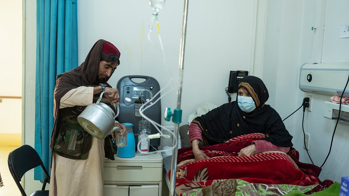 An Afghan man prepares tea for a relative being treated for COVID-19 in the emergency ward of the Afghan-Japan Hospital, in Kabul, Afghanistan, on Thursday, Dec. 9, 2021. Afghanistan's health care system, is on the brink of collapse and able to function only with a lifeline from aid organizations.