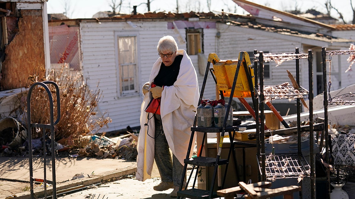 Martha Thomas stays warm with a bed comforter as volunteers help her salvage possessions from her destroyed home in the aftermath of tornadoes that tore through the region, in Mayfield, Kentucky, Monday, Dec. 13, 2021. 