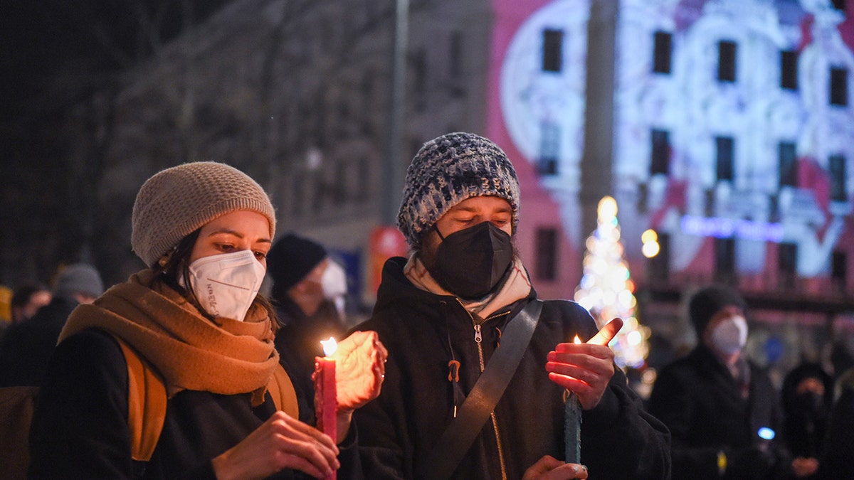 People hold candles to mourn the victims of COVID-19 during an event in Vienna, Austria, Dec. 19, 2021. 