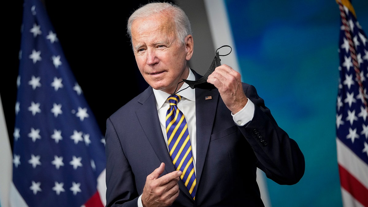 President Biden removes his face mask as he arrives to speak in the South Court Auditorium on the White House campus Oct. 14, 2021, in Washington, D.C. 