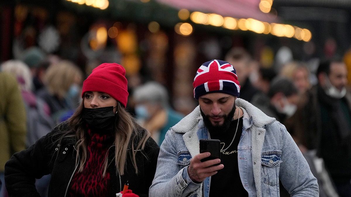 People walk past a Christmas market in Trafalgar Square in London, Wednesday, Dec. 22, 2021. British Prime Minister Boris Johnson said on Monday that his government reserves the "possibility of taking further action" to protect public health as Omicron spreads across the country.
