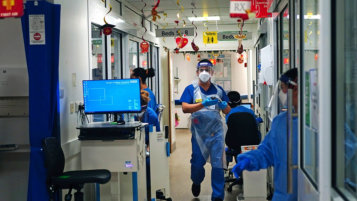 Medical staff wearing PPE,  on a ward for COVID-19 patients at King's College Hospital, in southeast London, Tuesday, Dec. 21, 2021. 