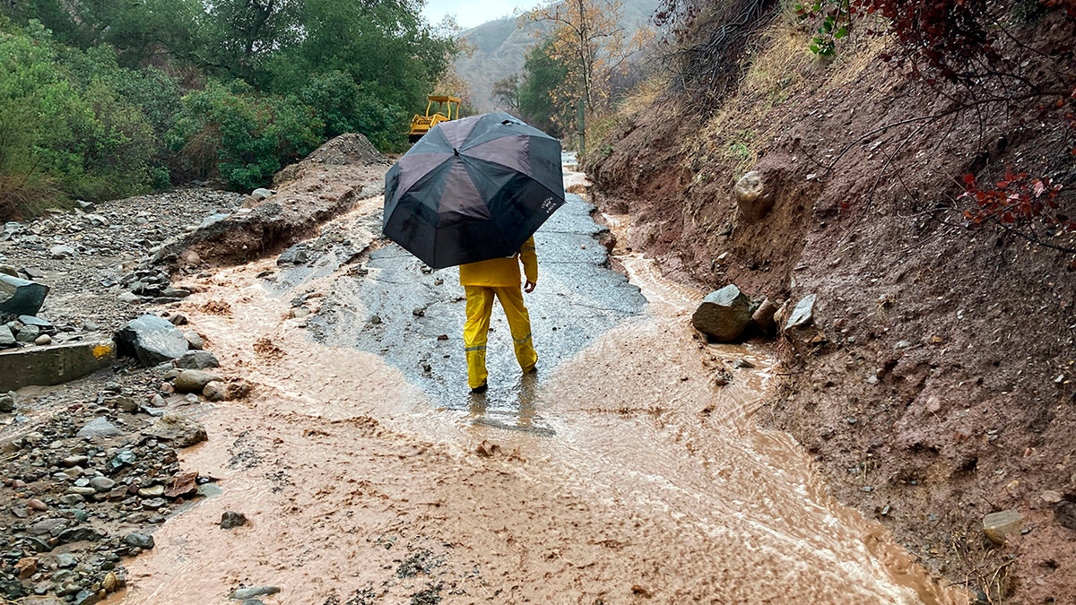A local resident surveys the damage to a washed-out road in Silverado Canyon, California, Tuesday, Dec. 14, 2021. 