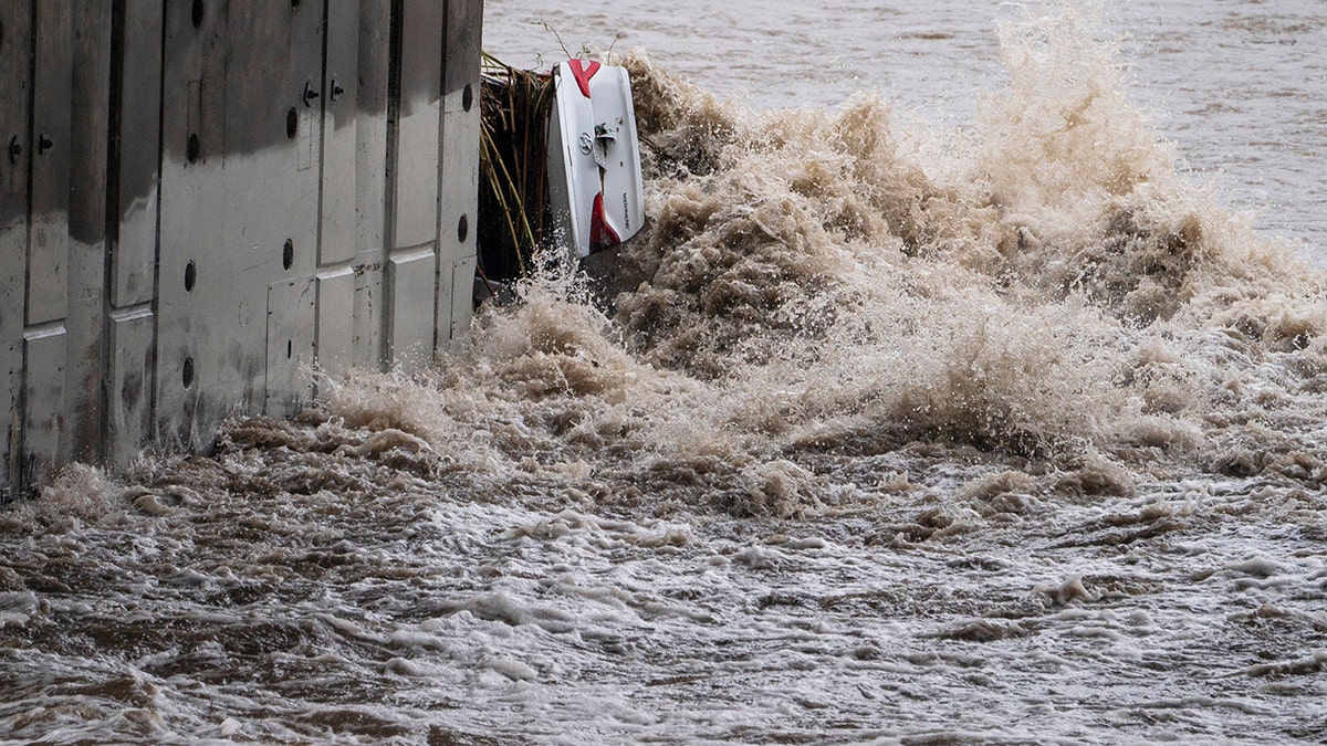 A submerged vehicle is wedged against a bridge pillar in the surging Los Angeles River making it difficult for firefighters to access it on Tuesday, Dec. 14, 2021 in Los Angeles. 