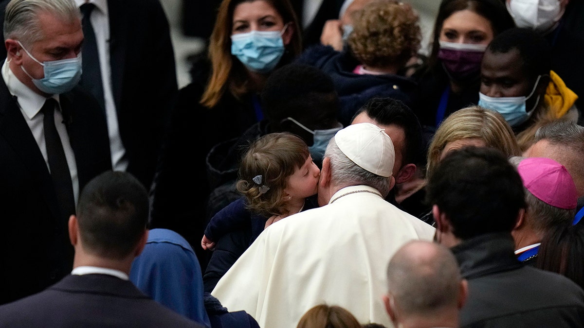 Pope Francis is kissed by a child at the end of his weekly general audience in the Paul VI Hall, at the Vatican, Wednesday, Dec. 22, 2021. 