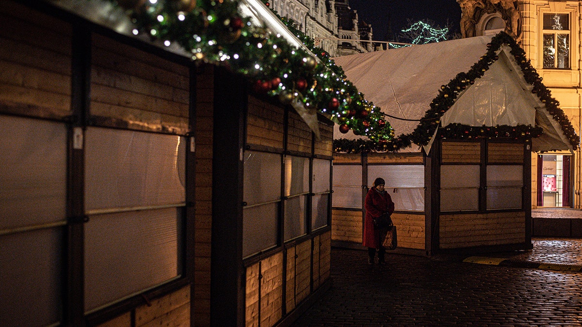 A woman stands next to closed booths as the traditional Christmas market at the Old Town Square has been cancelled due to COVID-19 concerns, in Prague, Czech Republic, on Nov. 29, 2021. 