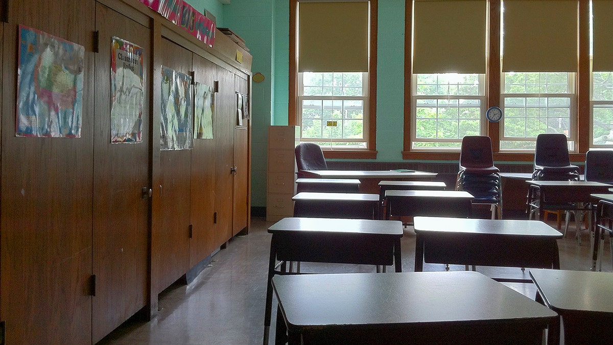 empty desks in classroom, windows in background