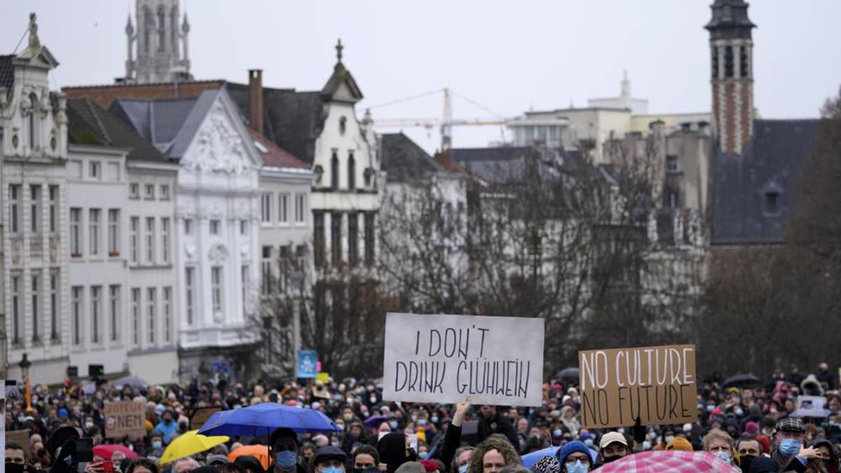 A man holds a sign which reads 'I don't drink Gluhwein' as he protests with other artists during a demonstration in Brussels on Sunday, Dec. 26, 2021. Belgian performers, cinema operators, event organizers and others joined together Sunday to protest the government's decision to close down the country's cultural life to stem the spread of the surging omicron virus variant. Gluhwein refers to a common drink which is served at Christmas markets.