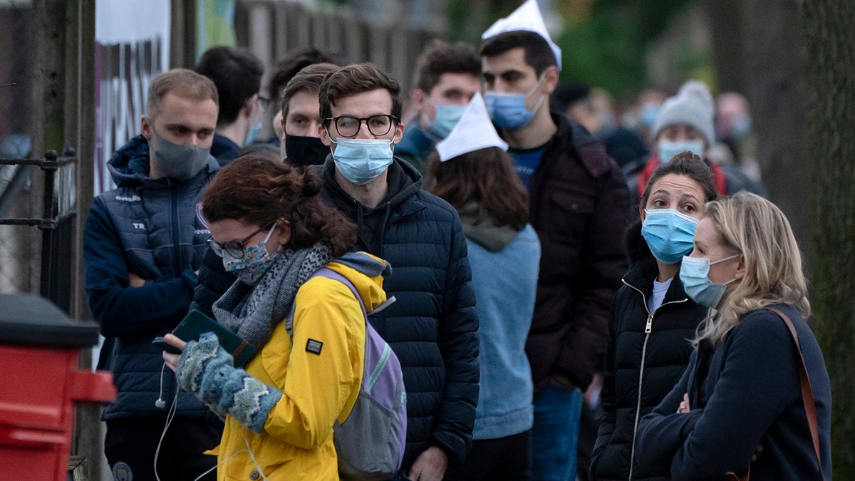 People queue outside a vaccination center in Manchester, England, Monday, Dec. 13, 2021