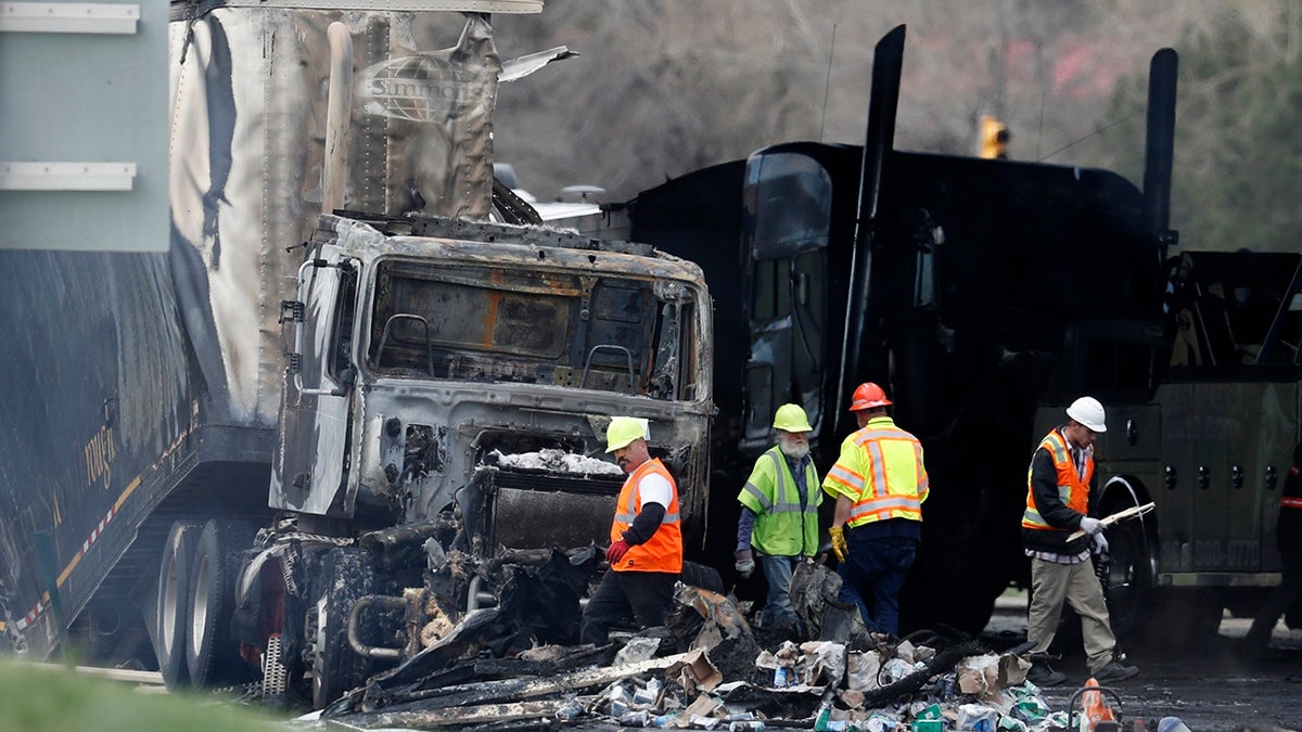 FILE - Workers clear debris from the eastbound lanes of Interstate 70 on April 26, 2019, in Lakewood, Colo., following a deadly pileup involving a semi-truck hauling lumber. A truck driver who was convicted of causing the fiery pileup that killed four people and injured six others on Interstate 70 west of Denver was sentenced Monday, Dec. 13, 2021, to 110 years in prison. Rogel Aguilera-Mederos was convicted in October of vehicular homicide and other charges stemming from the April 2019 crash. (AP Photo/David Zalubowski, File)