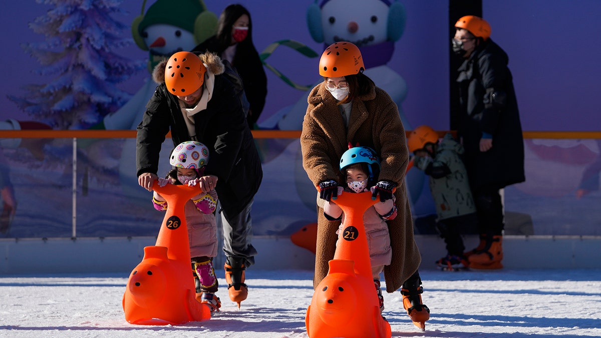 People bring their children to play during the weekend holiday outside a shopping mall in Beijing, Sunday, Dec. 26, 2021. 