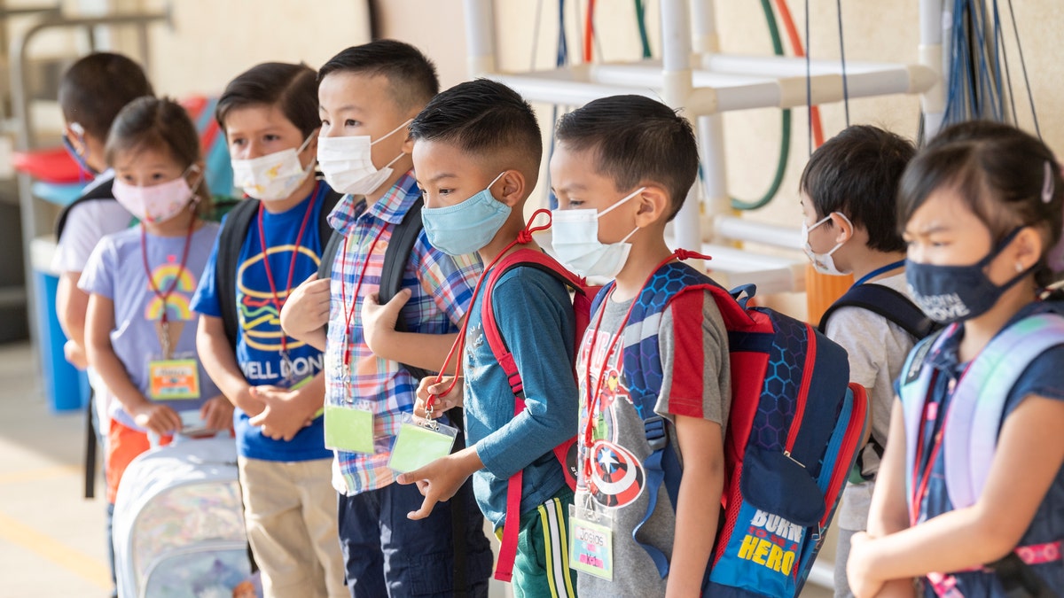 Masked students wait to go to their classroom during the first day of class at Stanford Elementary School in Garden Grove, California, on Monday, August 16, 2021. 