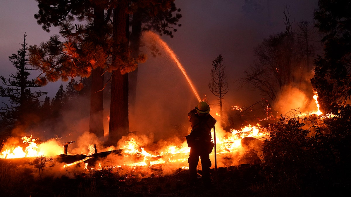Firefighter Elroy Valadez sprays water over a spot fire from the Caldor Fire burning along Highway 89 near South Lake Tahoe, California, on Sept. 2, 2021