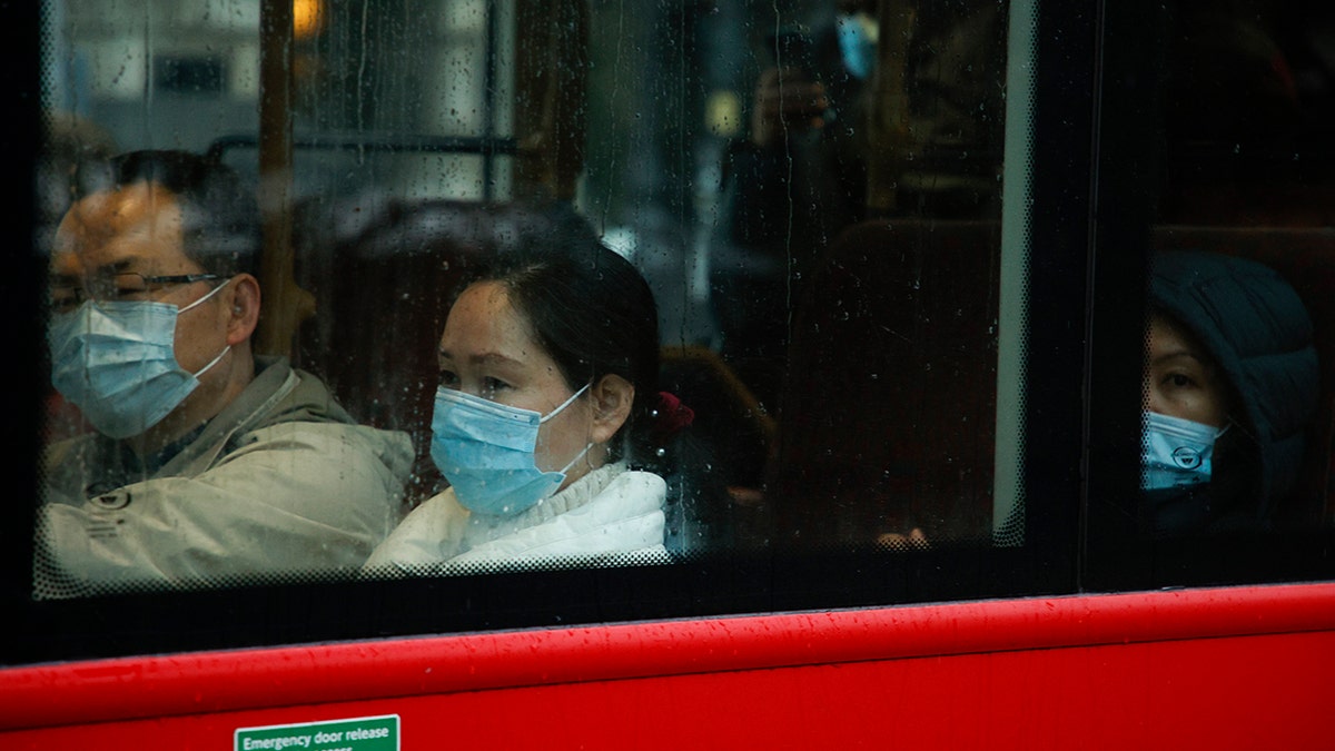 Passengers wearing face masks ride a bus through Westminster in London, Monday, Dec. 27, 2021. 