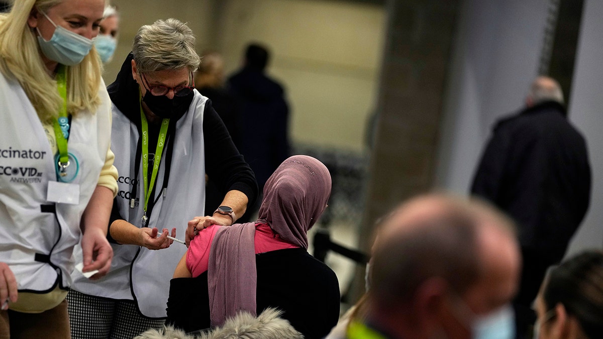 A vaccinator administers a Moderna booster vaccine to a woman at the Antwerp Expo vaccine center in Antwerp, Belgium, on Monday, Dec. 27, 2021. 