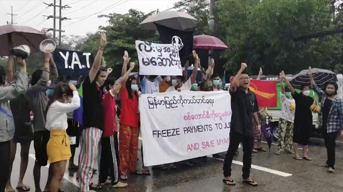 Protesters hold signs in Yangon on Oct. 30, 2021, calling for the freezing of revenues from oil and gas sales in Burma.