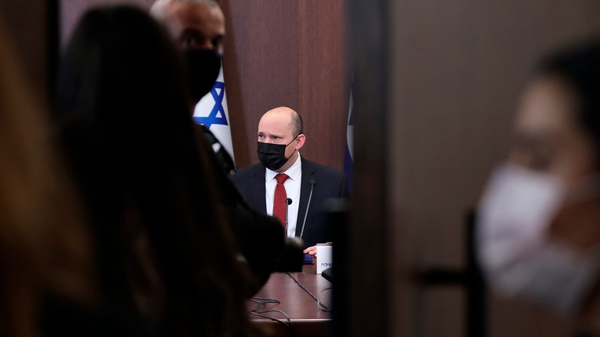Israeli Prime Minister Naftali Bennett, rear and wearing a face mask, attends during a cabinet meeting at the prime minister's office in Jerusalem, Israel, Sunday, Dec. 19, 2021. 