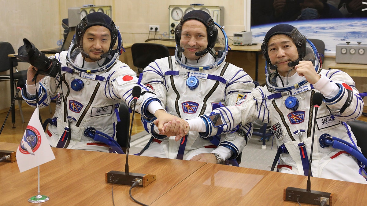 Alexander Misurkin, center, Yusaku Maezawa, right, and Yozo Hirano pose prior to the launch Wednesday, Dec. 8, 2021. 