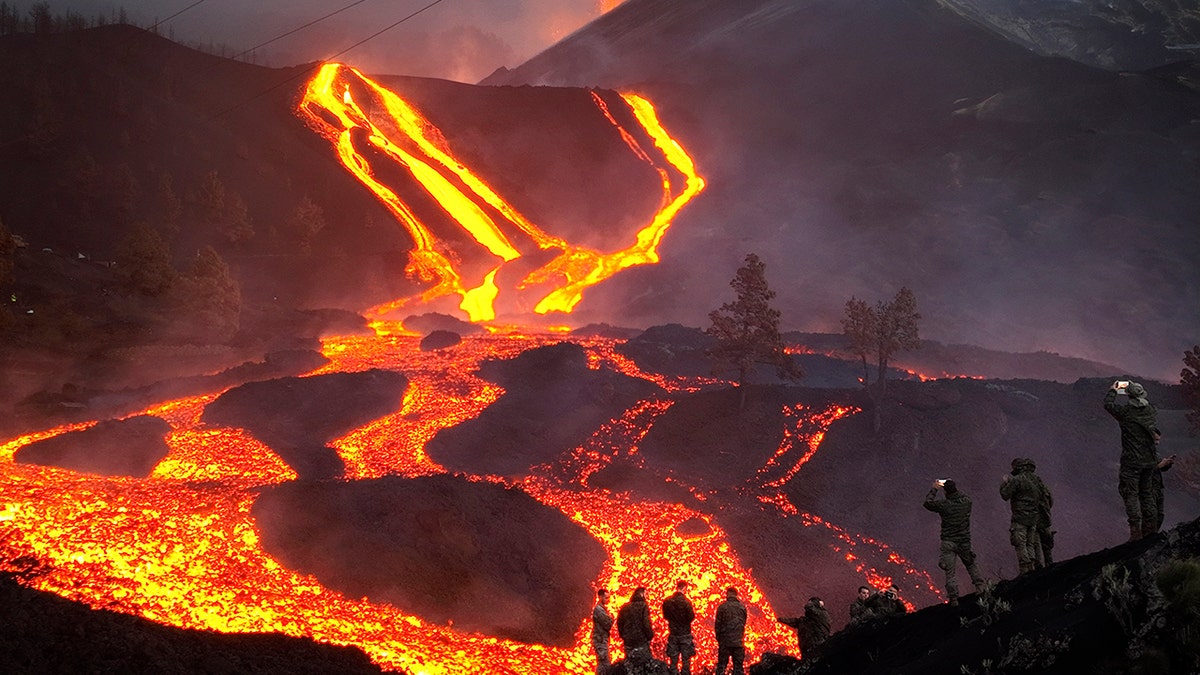 Spanish soldiers stand on a hill as lava continues to flow on the Canary island of La Palma, Spain, Monday, Nov. 29, 2021. 