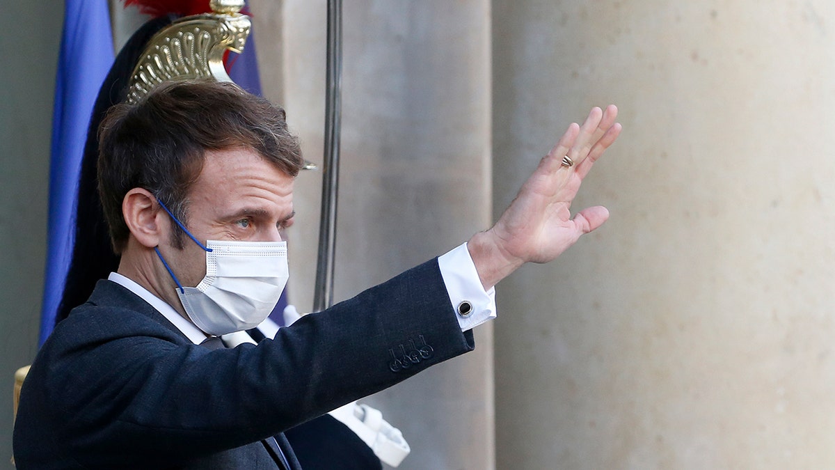 French President Emmanuel Macron wearing a protective face mask waves as German Chancellor Olaf Scholz leaves the Elysee Presidential Palace after their working lunch on Dec. 10, 2021 in Paris, France.  