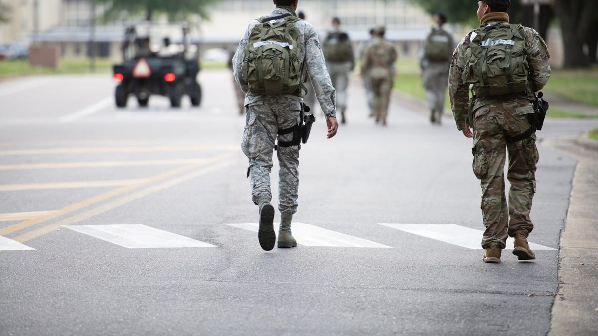 Soldiers in camouflage fatigues walk on a road at Maxwell Air Force Base