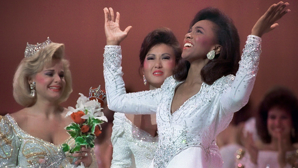 Miss America 1989 Gretchen Carlson, left, and Maryland's Virginia Cha watch as Missouri's Debbye Turner throws her arms up in jubilation after winning Miss America 1990 in Atlantic City, New Jersey, Sept. 16, 1989. 
