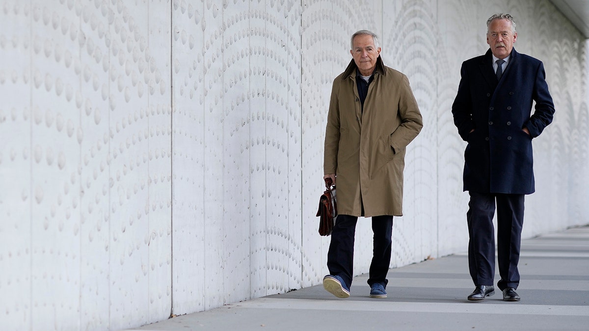 Anton Kotte, left, who lost his son, daughter-in-law and grandson, and Piet Ploeg, who lost his brother, sister-in-law and nephew, arrive outside the court for the ongoing trial and criminal proceedings regarding the downing of Malaysia Airlines flight MH17, at the high security court at Schiphol airport, near Amsterdam, Netherlands, Monday Dec. 20, 2021.