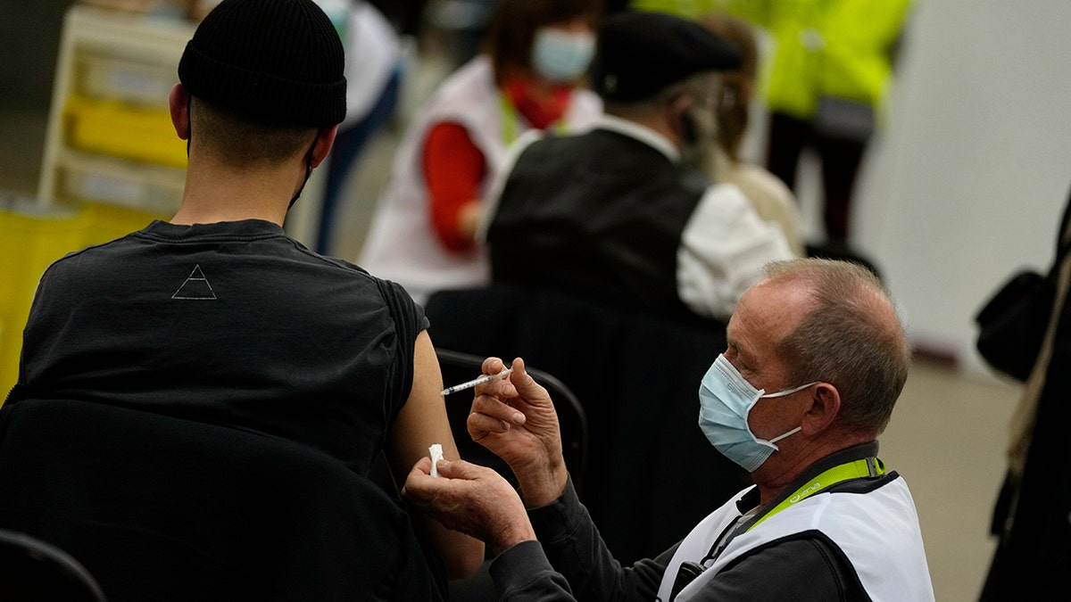 A vaccinator administers a Moderna booster vaccine to a man at the Antwerp Expo vaccine center in Antwerp, Belgium, on Monday, Dec. 27, 2021. 