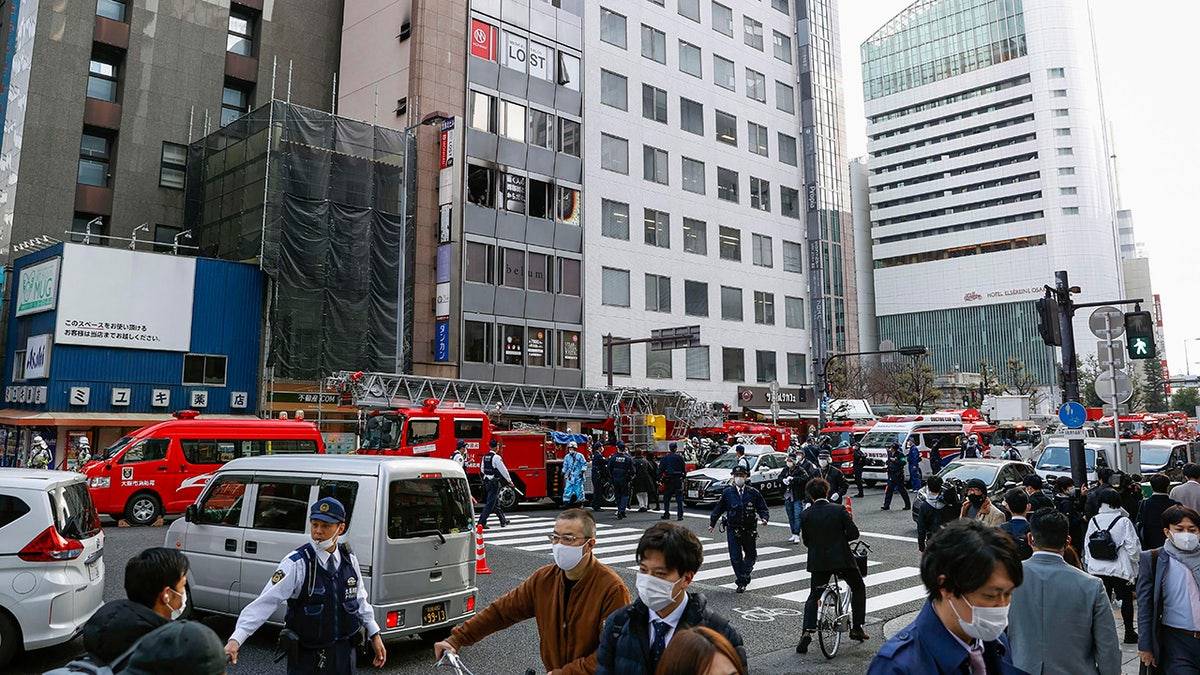 Fire engines park near a building, center in the background, where a fire broke out in Osaka, western Japan Friday, Dec. 17, 2021. (Yukie Nishizawa/Kyodo News via AP)